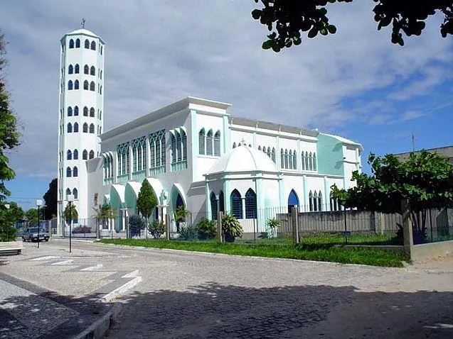 Catedral Nossa Senhora Auxiliadora, de paredes brancas e detalhes verdes, com sua torre alta, em Eunápolis